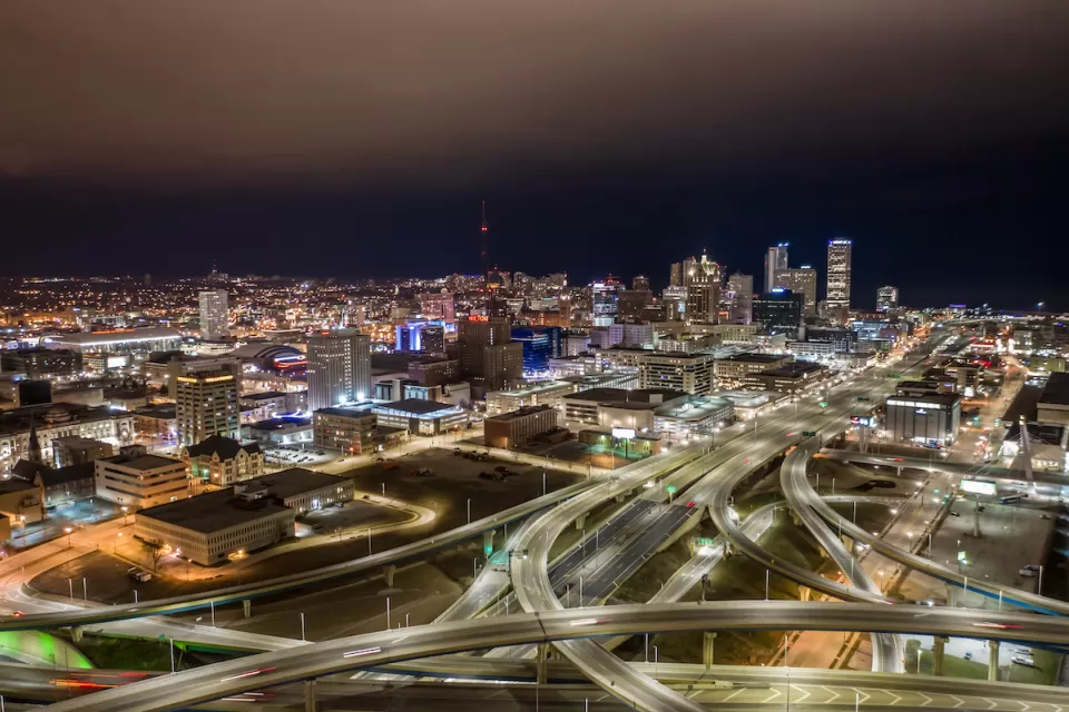 Aerial view of Milwaukee, Wisconsin skyline with freeway interchanges in foreground at night.